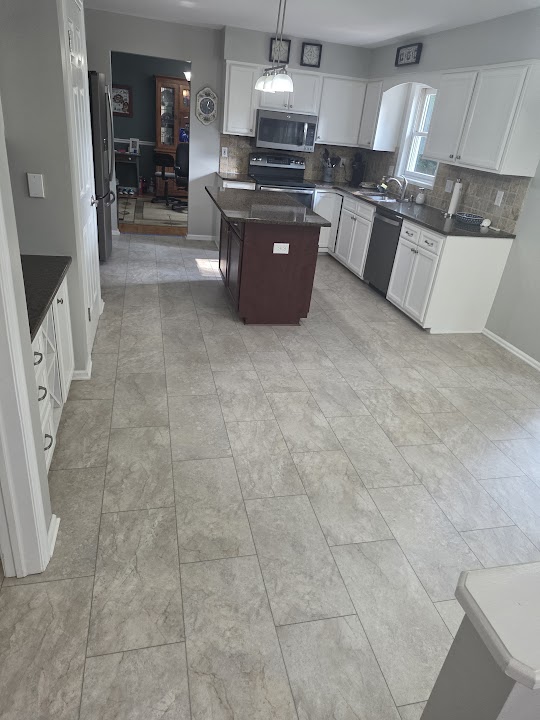 Light rectangular floor tiles in a kitchen with white cabinets and a central island