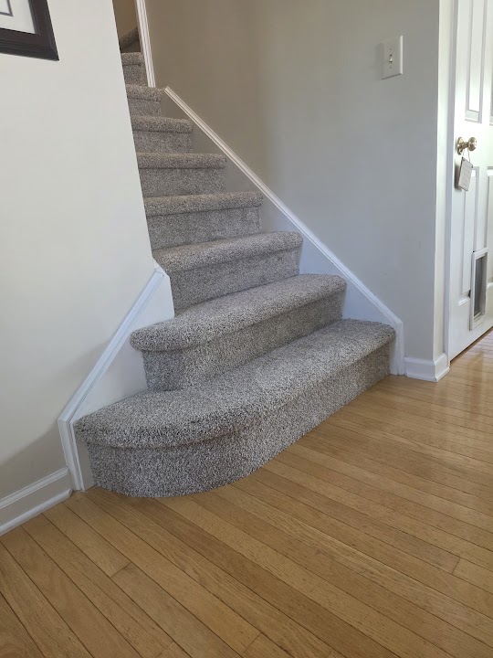 Gray carpeted staircase with curved lower steps